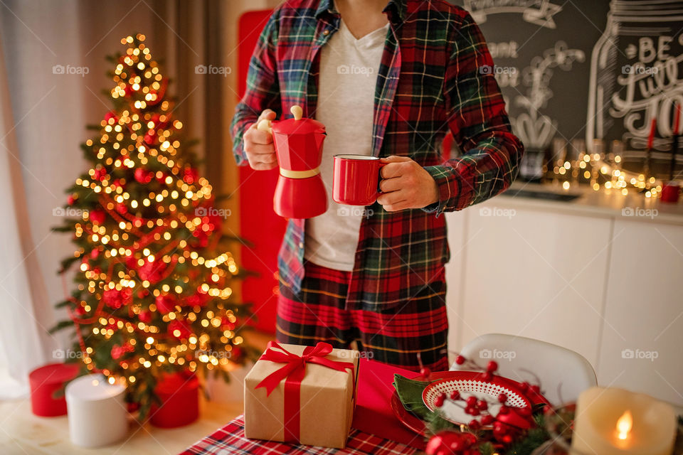 Festive winter cozy kitchen interior with garlands, decorations and gifts.  Christmas dinner at the decorated table.