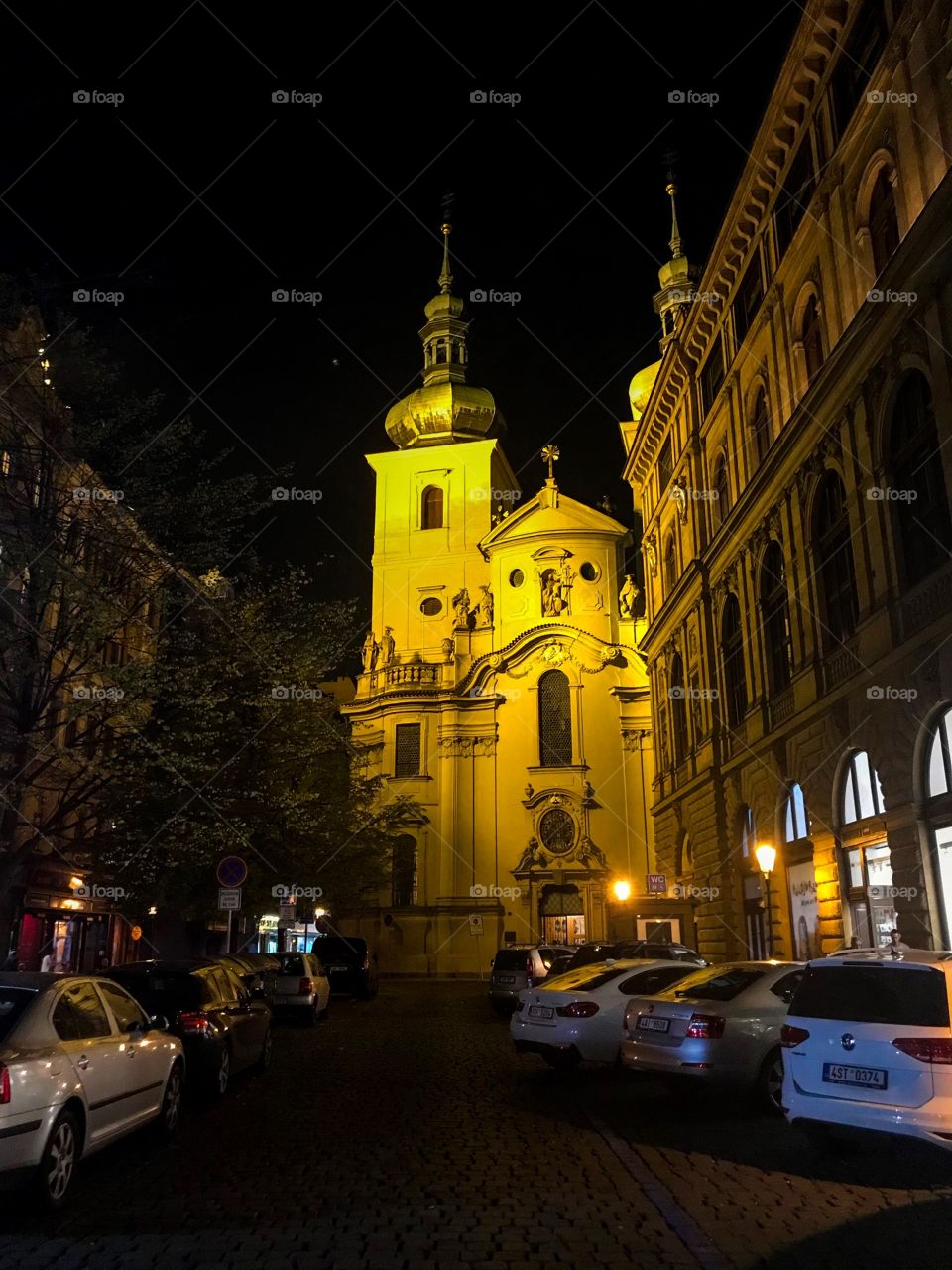 A church on the street at night,cars parked, buildings at 2 side,a few yellow street lights, in the very dark sky. I saw it when I walking around the streets in the city
