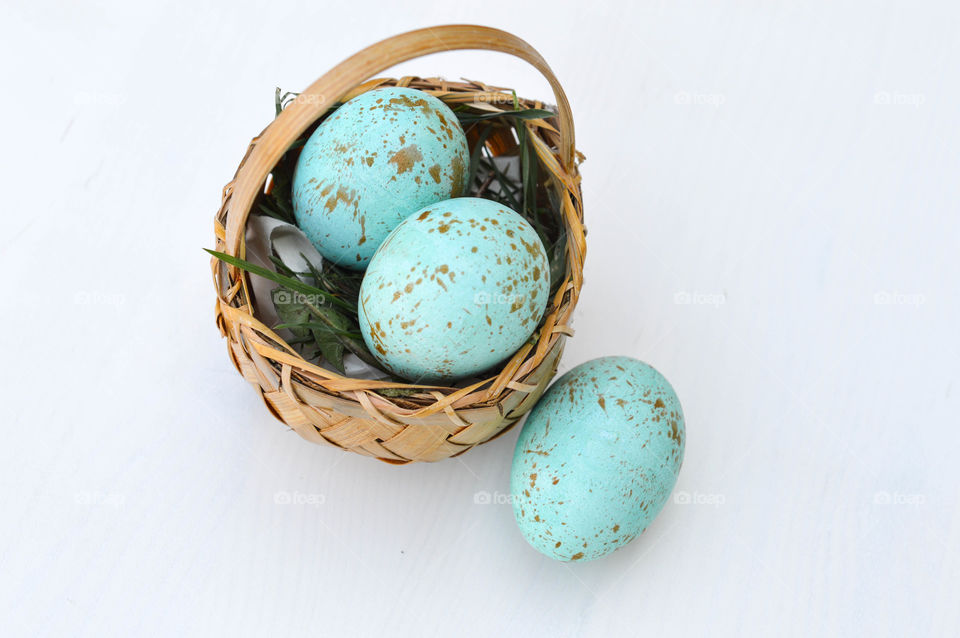 Painted robin eggs in a small basket indoors