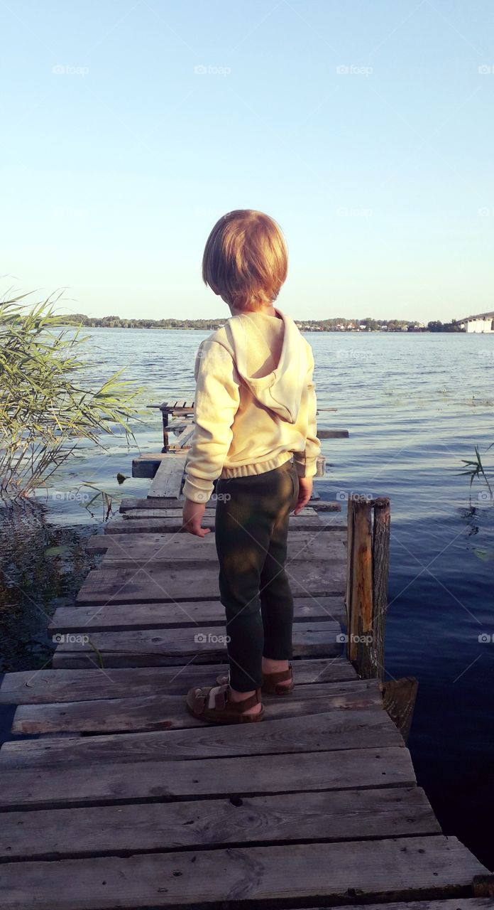 boy on a wooden bridge near the river