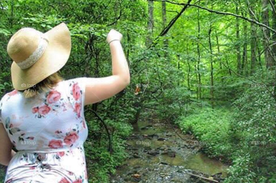 A woman throwing pebbles into a stream