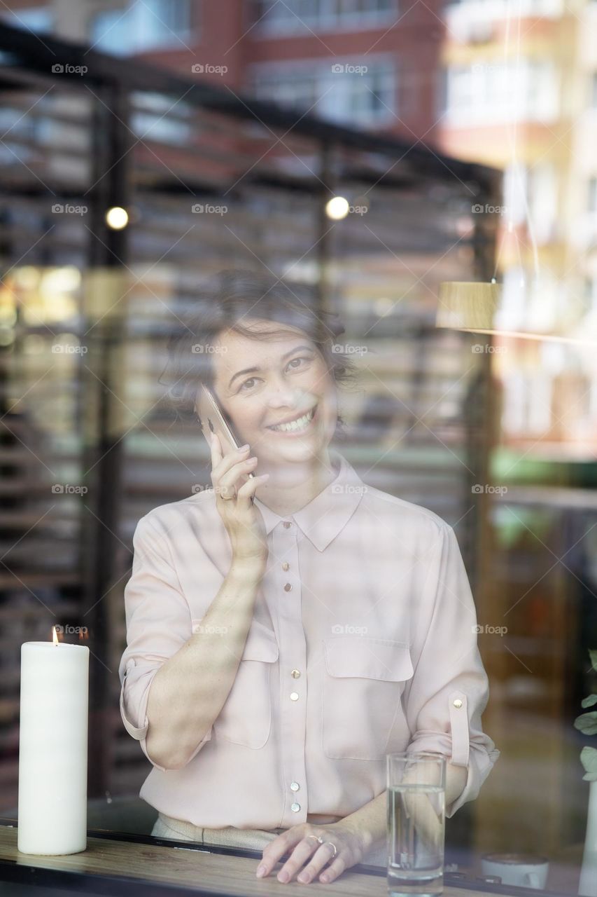 The girl with the phone in her hand smiles. The girl in the window