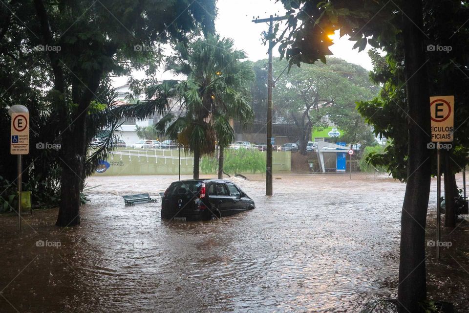 Car on a heavy rain day, on a flood, flooded street at Piracicaba, Brasil. 
Black car on the Waters of a flood in Brazil.