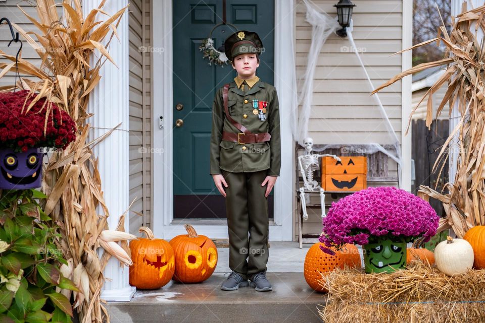 Young boy dressed in costume as a historical military officer for Halloween outside a decorated home