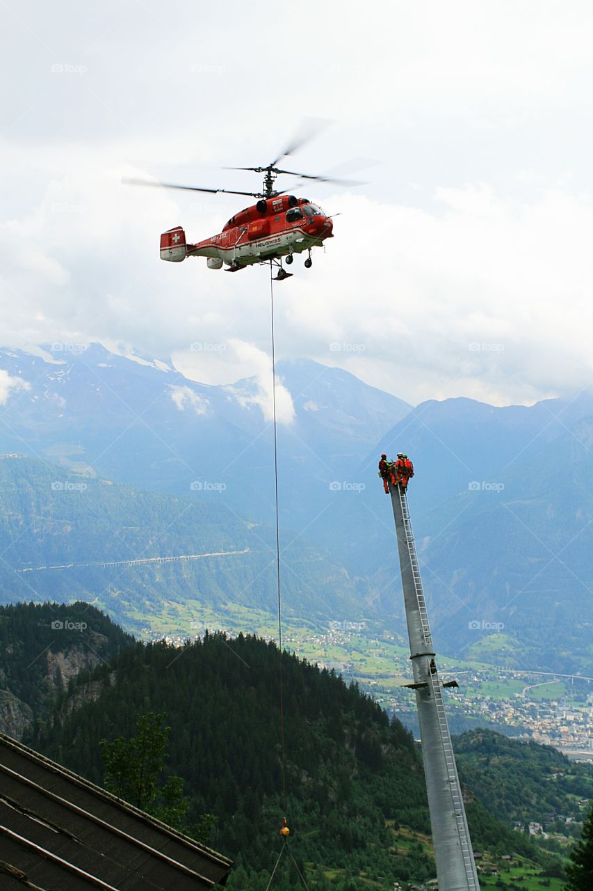 Swiss construction workers building a new skilift in the Swiss Alps, with help from a helicopter.