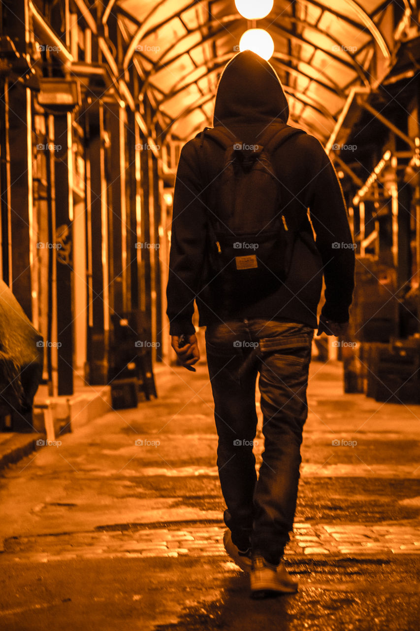 Young Man Walking On An Arcade At Night
