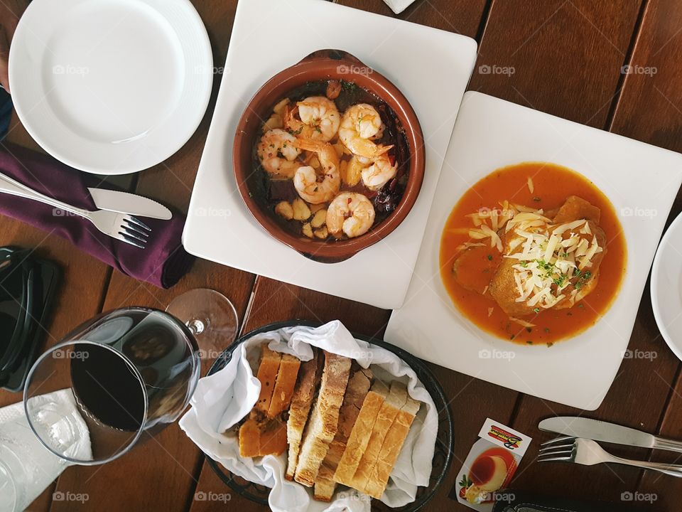 Wine, shrimp, breads and fresh eggplant flatly