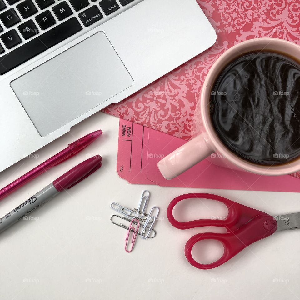 Pink flat lay of office workspace with office supplies, technology, cup of coffee and some white space