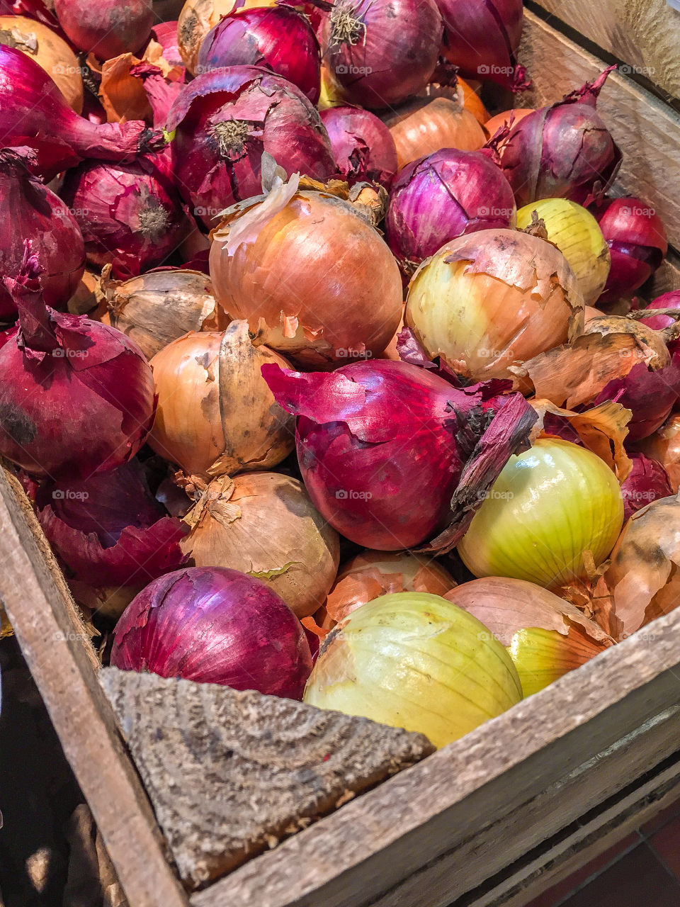 Wooden box with mixed food onions for sale at farmers market in Sweden in fall.