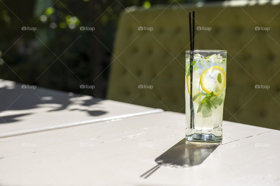 Cold lemonade on the table in sunny day. Fresh mojito with ice