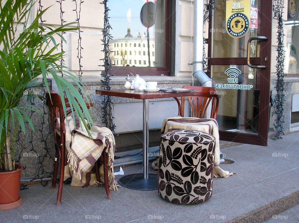 Table with chairs and blanket outside a coffeeshop