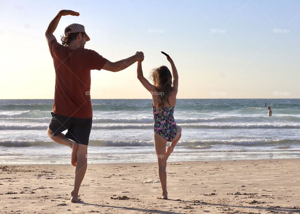 Father and daughter dancing on the beach 