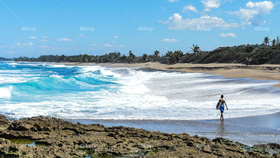 Man with surfboard walking on beach