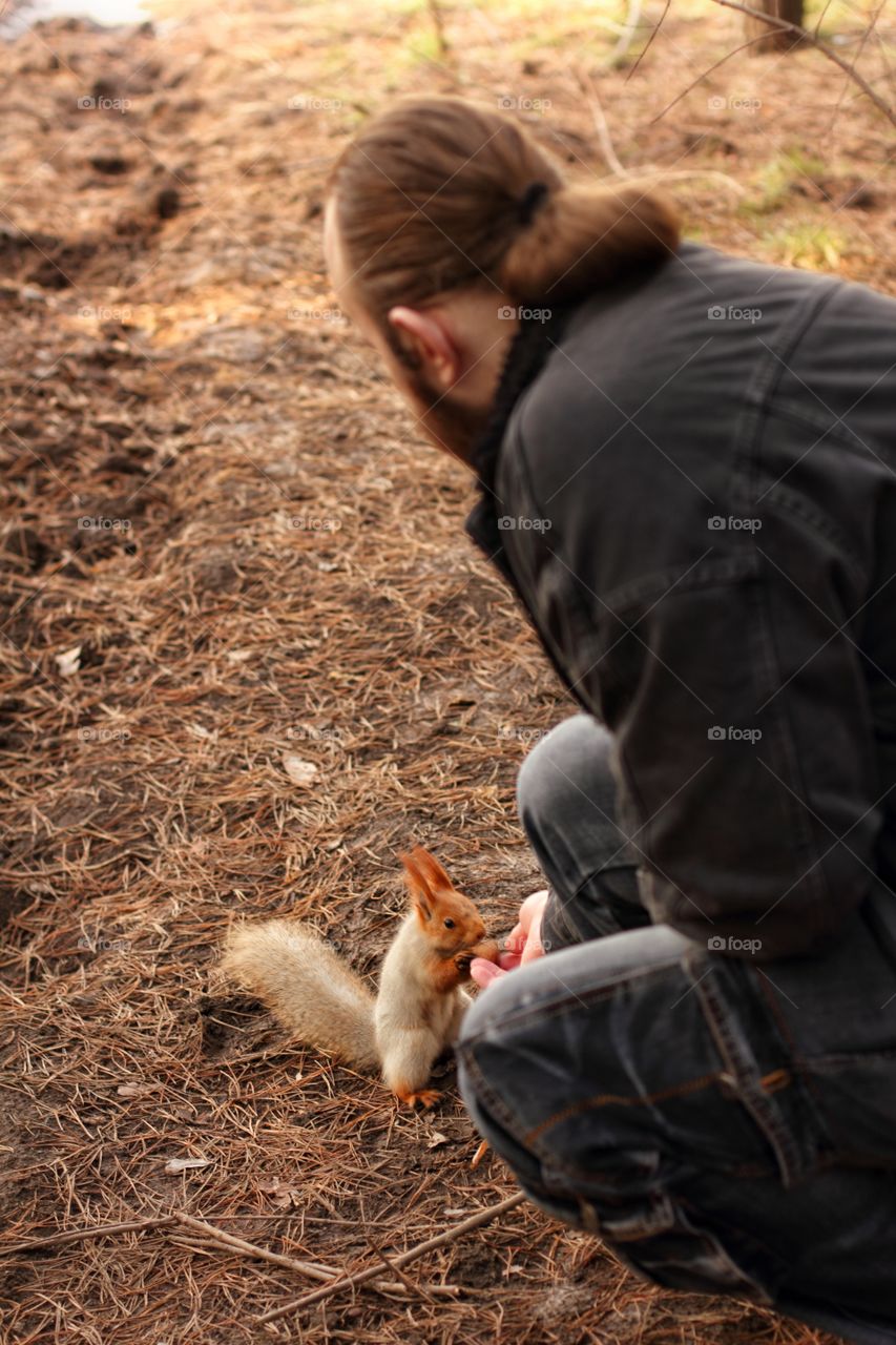 A man feeds a squirrel with nuts in a park
