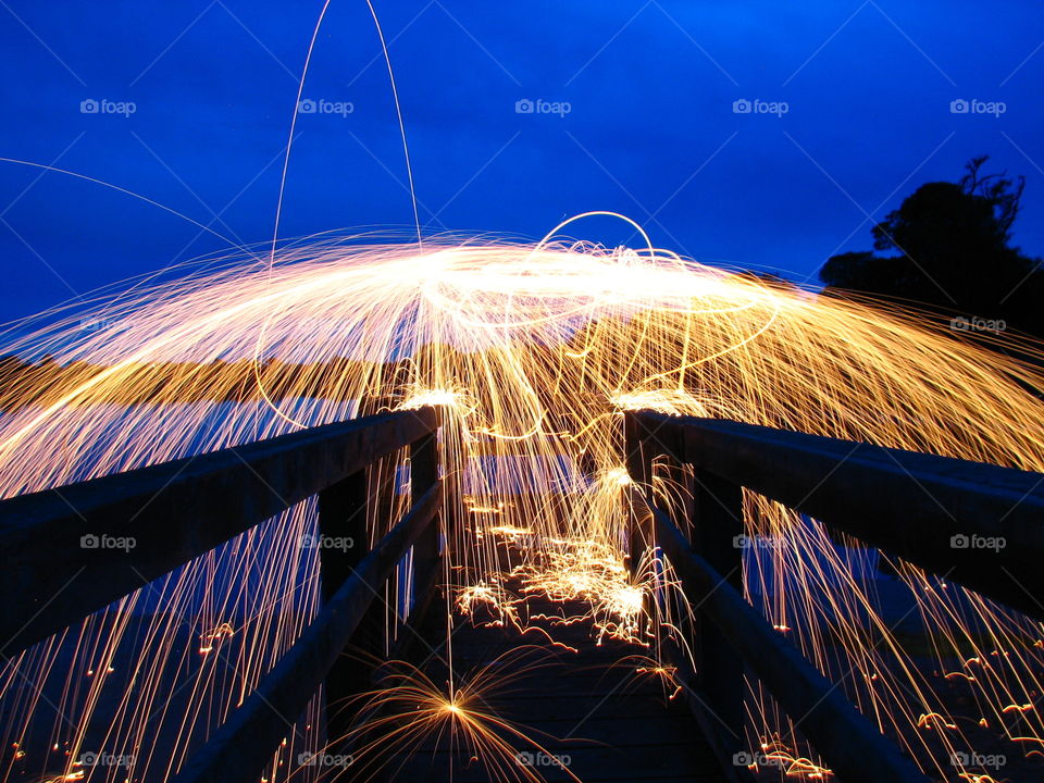 Steel wool sparks flying around the sky exploding like spiders