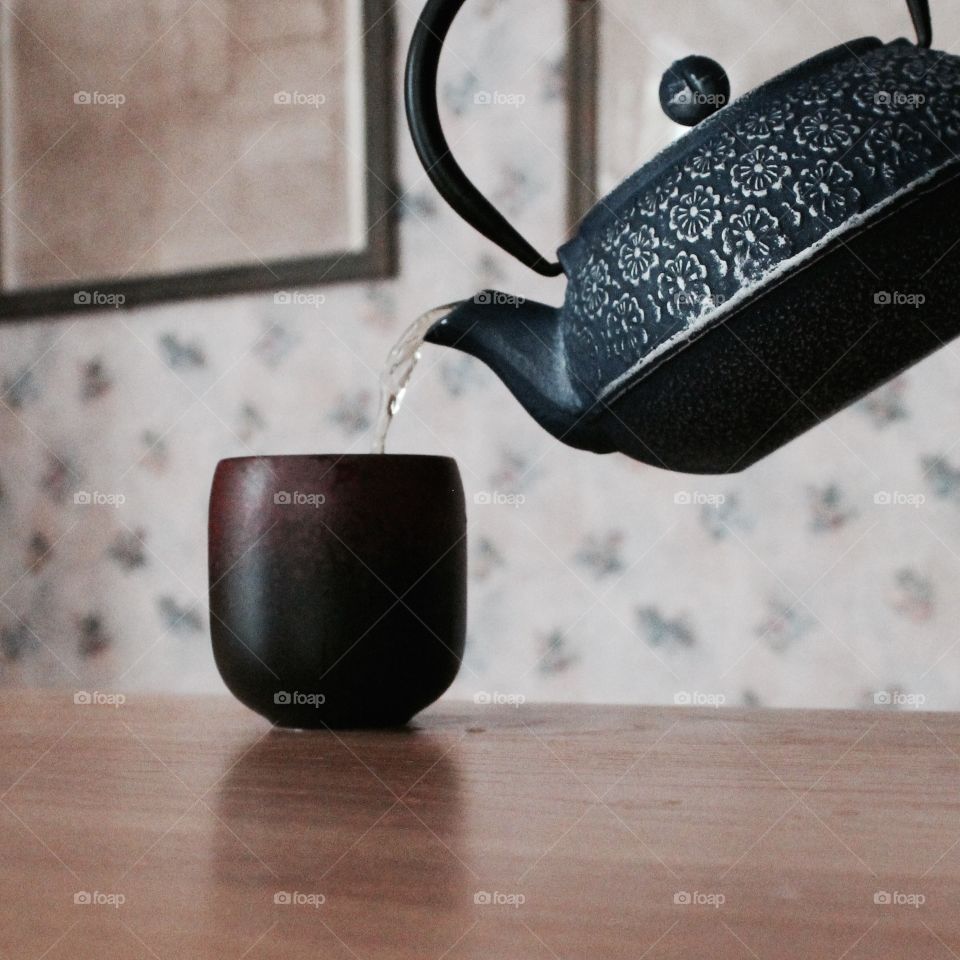 Kettle pouring water in cup