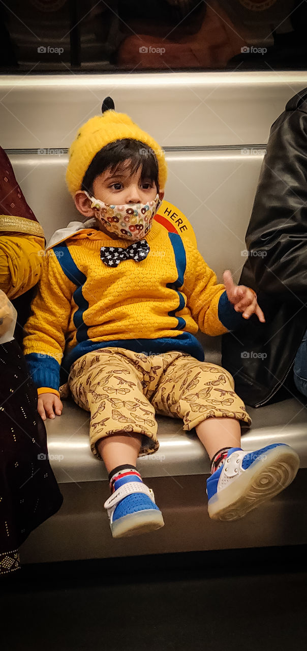 A kid with Yellow suit and a gray seat of metro