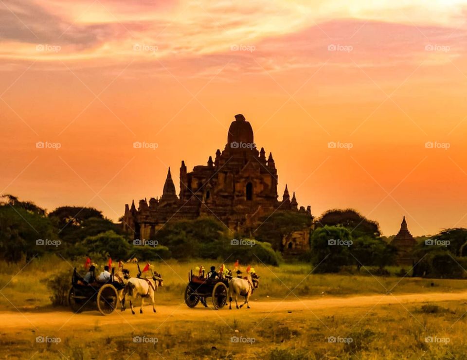 The old and the old. Horse carriages carry people in front of a pagoda in Bagan, Myanmar. Photo taken at sunset.