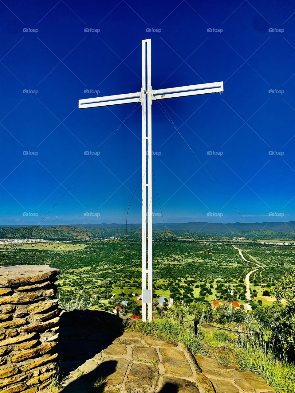 This robust old white rugged cross stands firm through all weathers on top of the mountain. Christians go there to pray. 