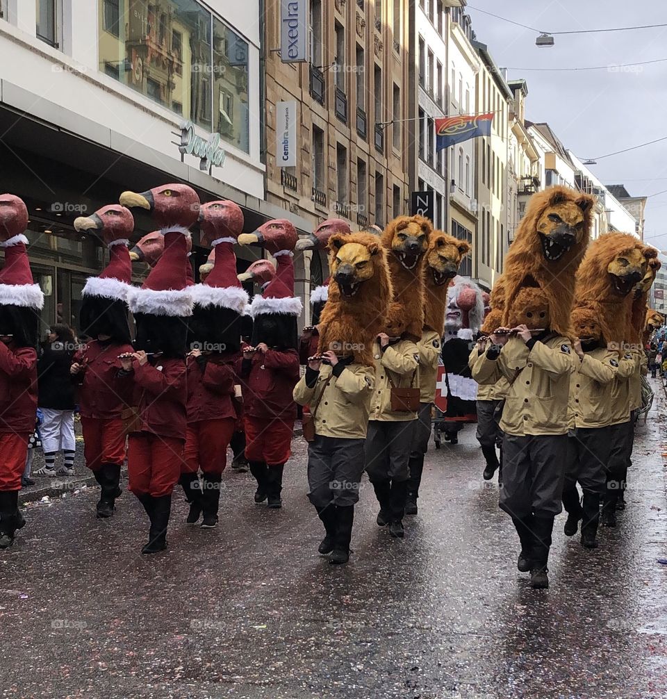 a large crowd of people running in the city among large buildings. a crowd of people in masquerade costumes and masks at a fundamental festival in Switzerland. people in bright costumes on a holiday
