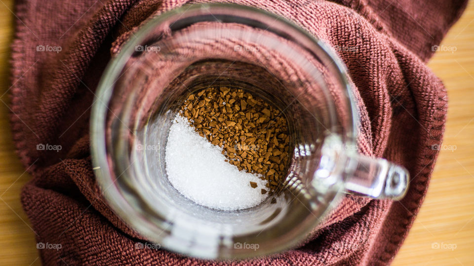 Transparent cup of coffee, diagonally diagonally poured sugar and instant coffee on the bottom