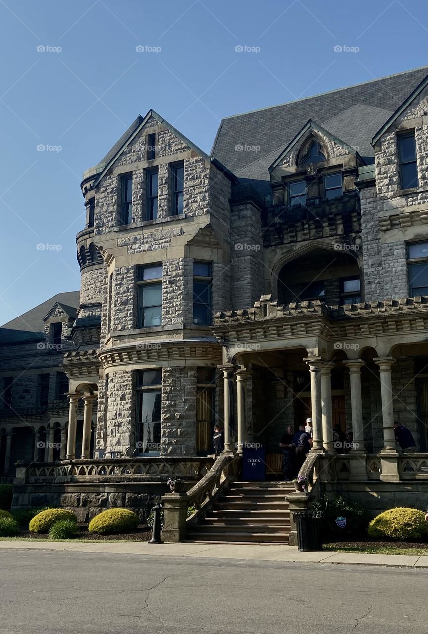 The front of a grey building that looks like a castle with stairs leading to the alcove
