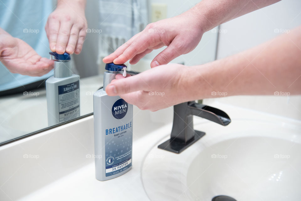 Man applying Nivea lotion to his hands next to a bathroom sink