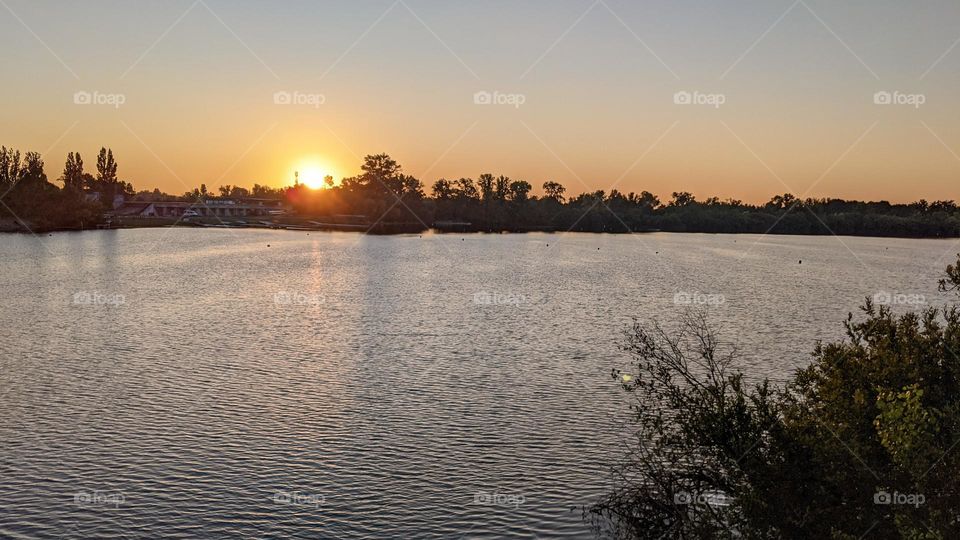 "The sun is sinking into the lake with a golden glow."