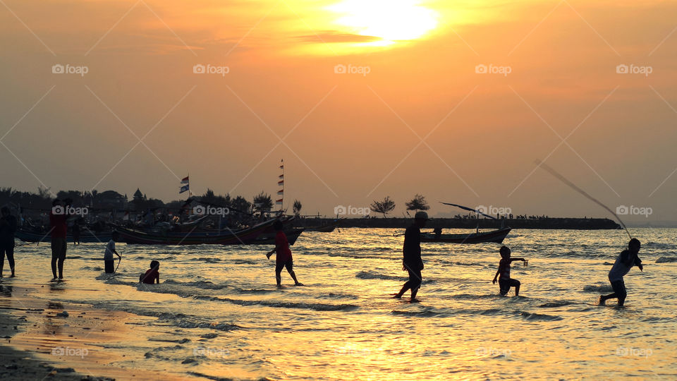 Some kids are playing happily during sunset at the beach of Tuban, East Java.