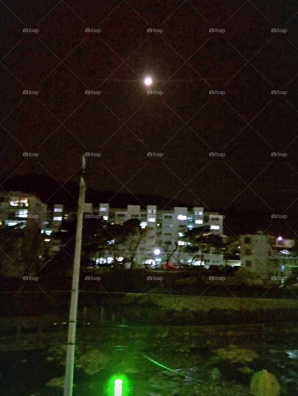 The moonlight in  yangsan South korea.

below the moon is the mountain and the apartments.
infront of apartments is a river bank.