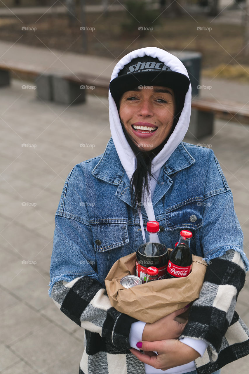 girl walks down the street and holds a package of Coca-Cola in her hands, spring, park