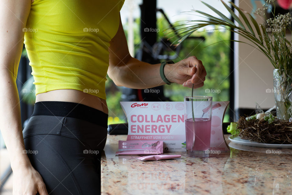 Female between 30 and 40 years old is preparing GOMO collagen energy before her morning cardio. GOMO collagen energy secondary packaging in the focus.
