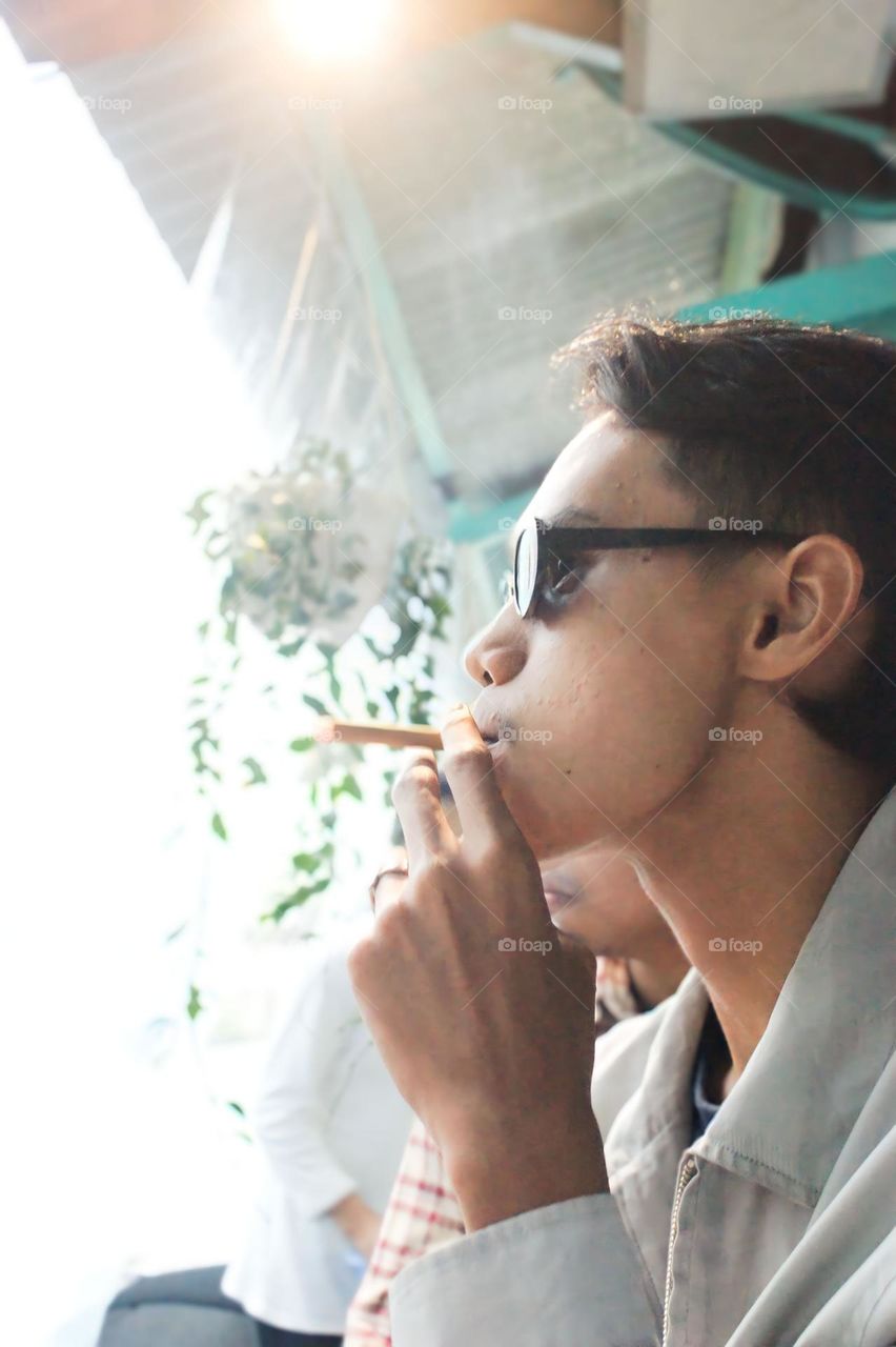 Side view of young man smoking cigarette