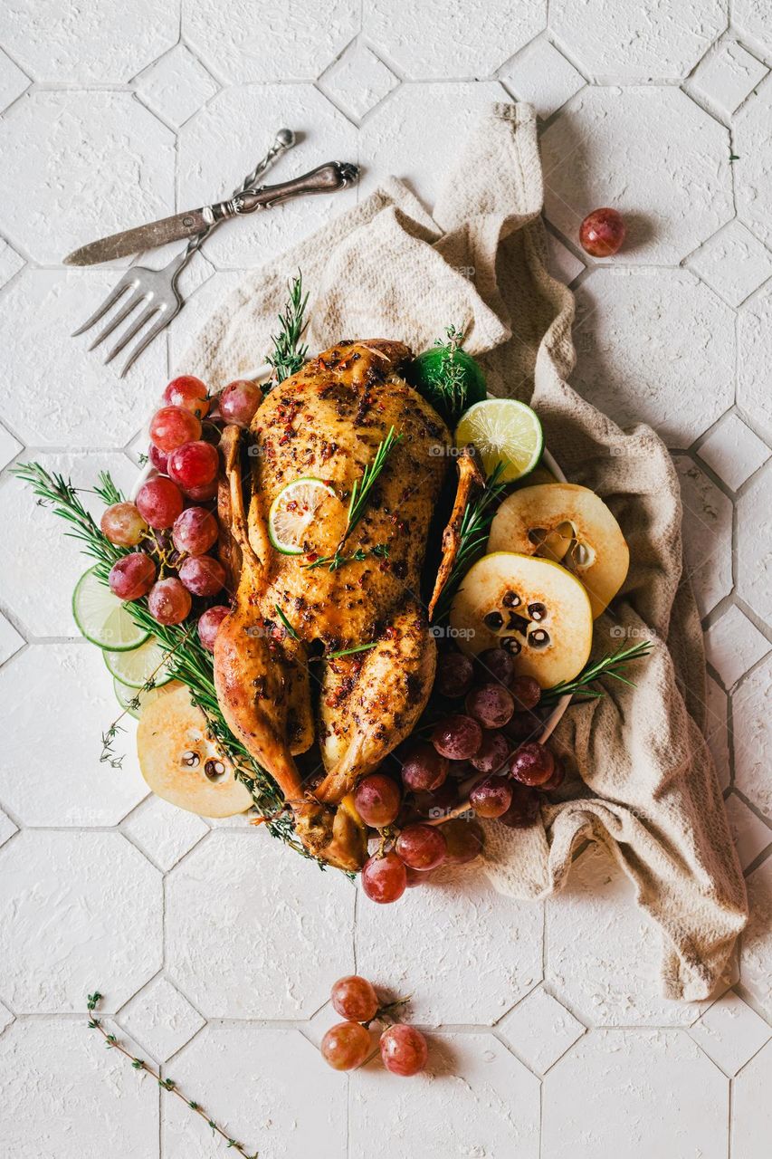 Golden turkey served to the table with quince, grapes and fragrant rosemary is a festive dinner, a restaurant dish. The pinnacle of the chef's skill. Home sweet home. Family holiday traditions.