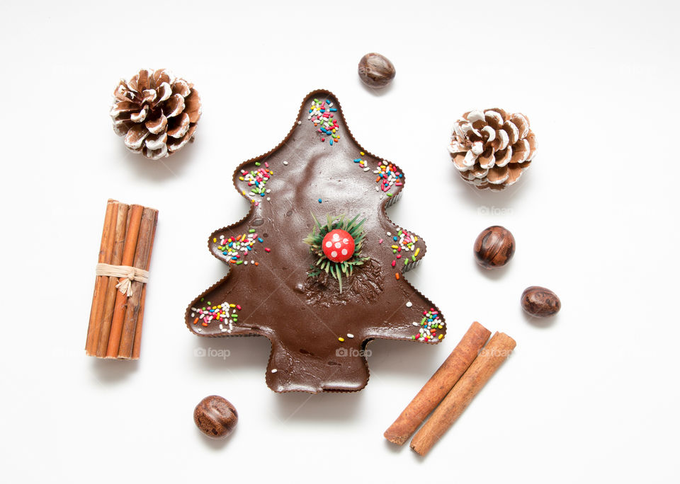 Composition Of Christmas Tree Chocolate Muffin Cupcake, Pine Cones, Nuts And Cinnamon Isolated On White Background
