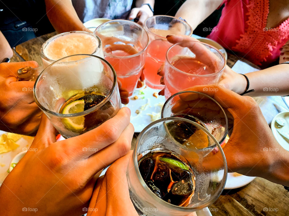 círculo de pessoas segurando copos de bebidas fazendo um drink