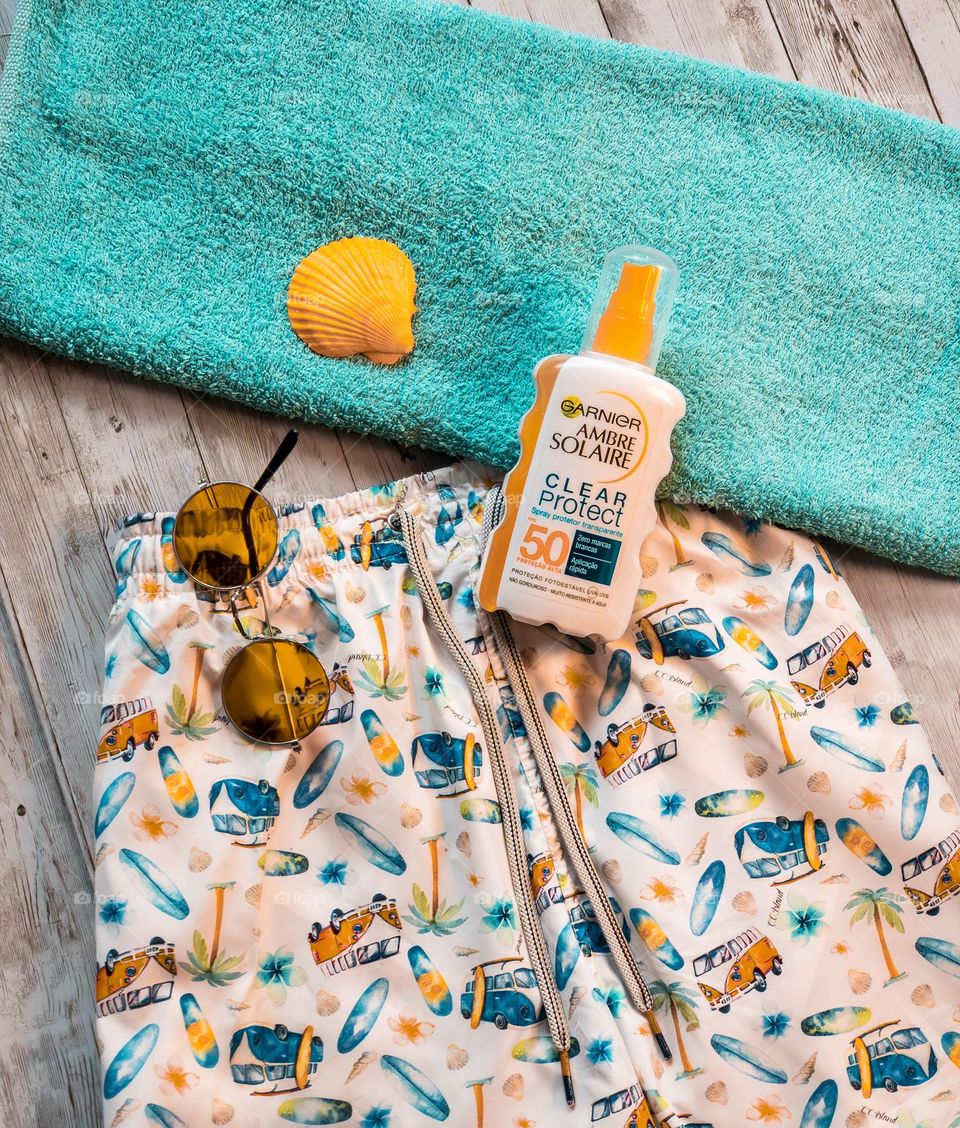 Swim shorts, sunglasses and towel with Ambre Solaire Suncream 