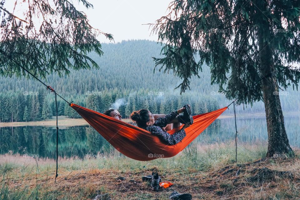 couple sitting in a hammok by a lake