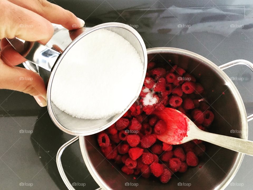 Cropped hand image pouring sugar in berry fruit