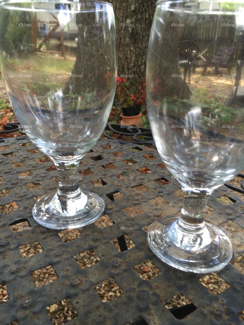Two empty wine glasses outdoors on a metal table.