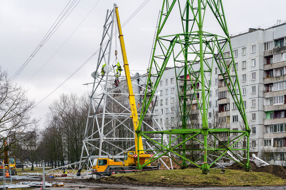 new high voltage power line steel support assembly in city, in the background of apartment buildings