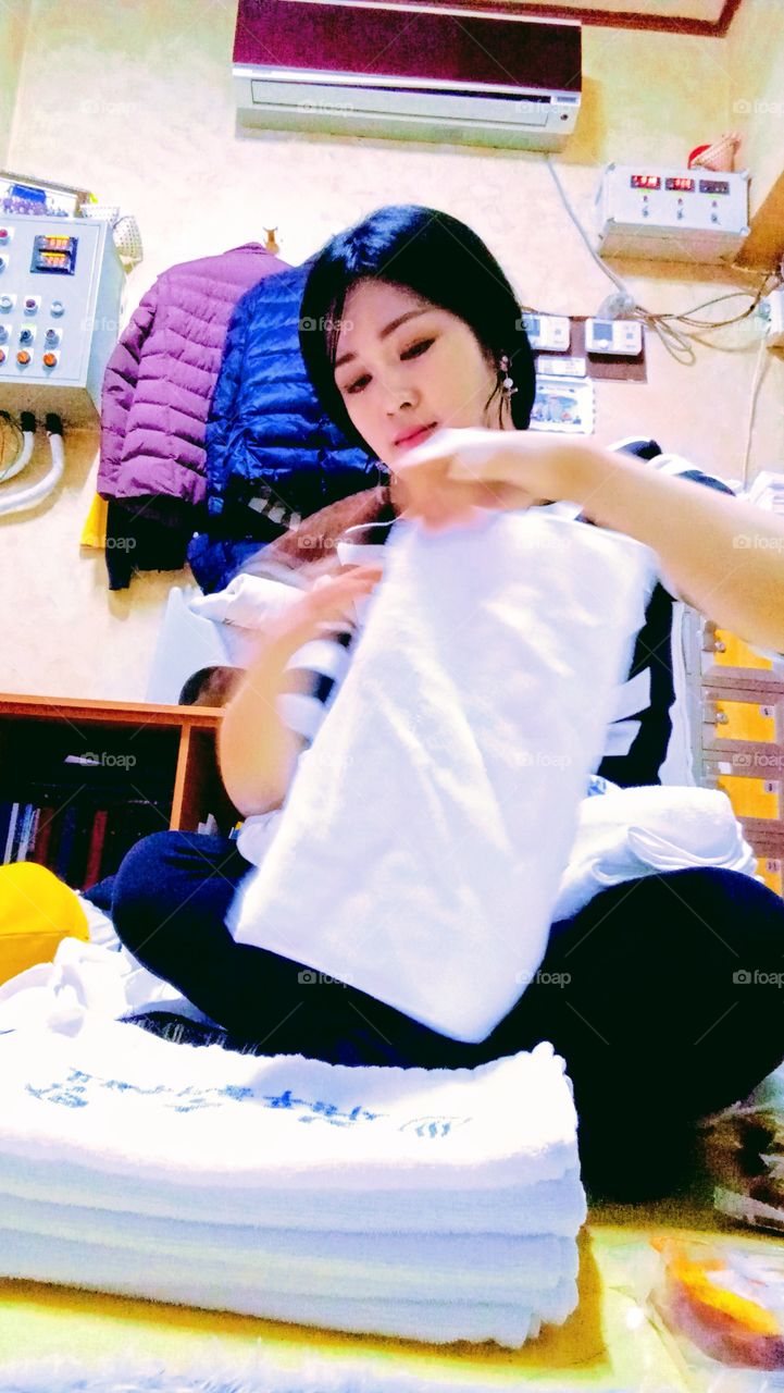 The woman is folding the shower towel  to fix it  for the customers,  as part of her work and obligation.