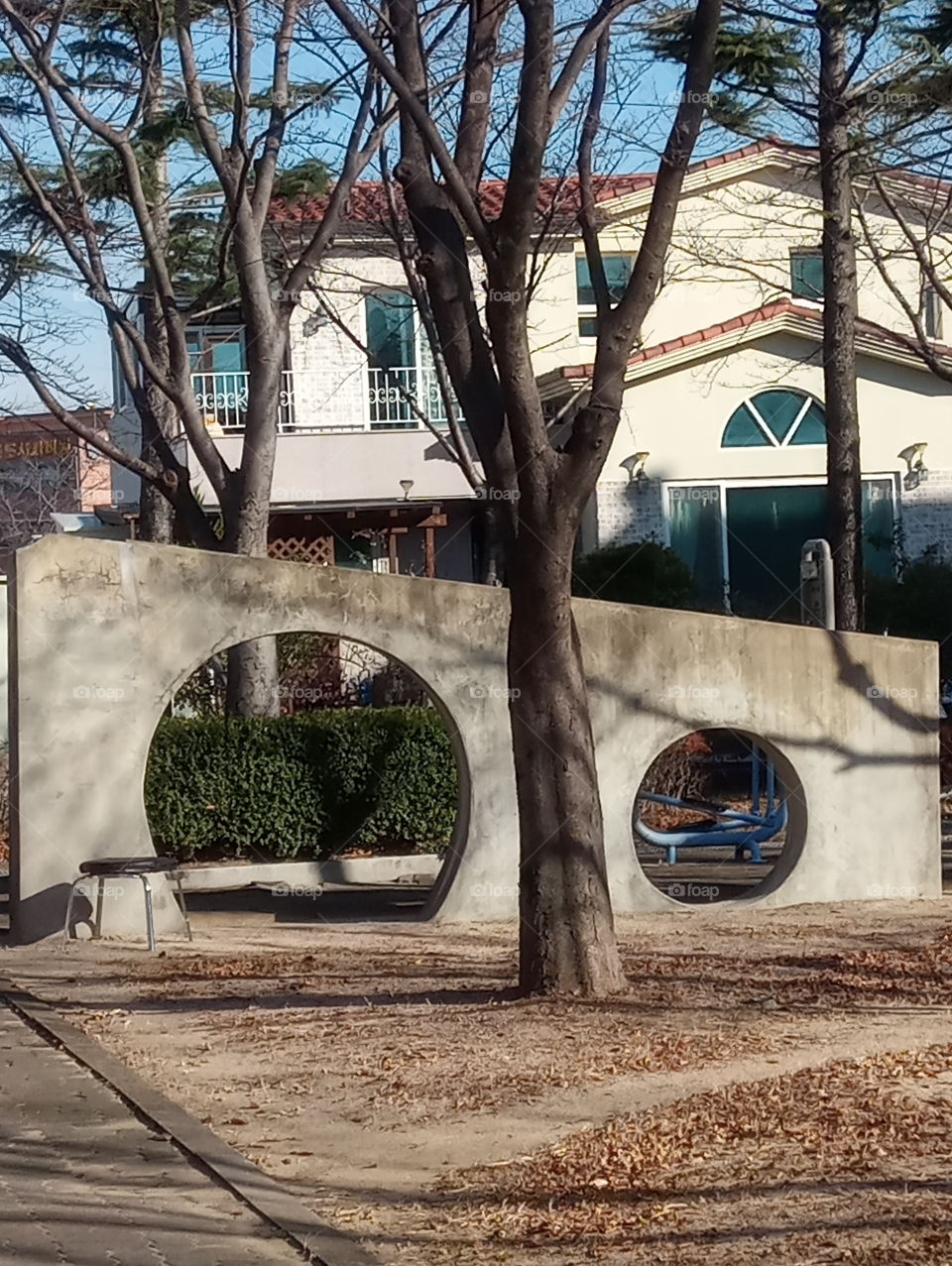 the white wall with  two big and small circle plus the big tree that stand infront of it makes it looks like and eyes and nose.