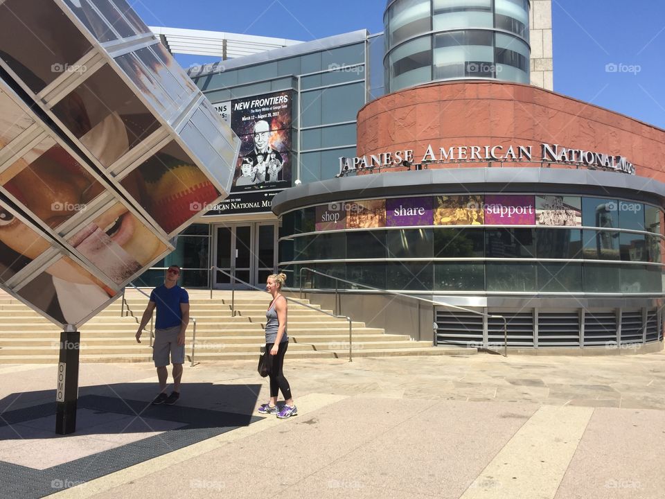 Visitors to the Japanese American National Museum spin the sculpture in front of the museum.