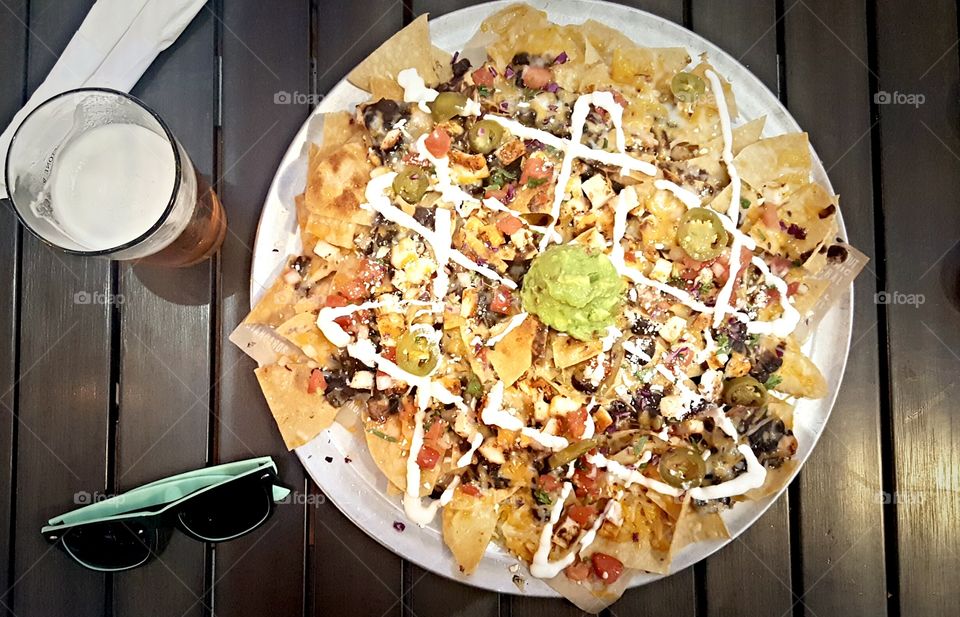 Close-up of nachos and beer on wooden table