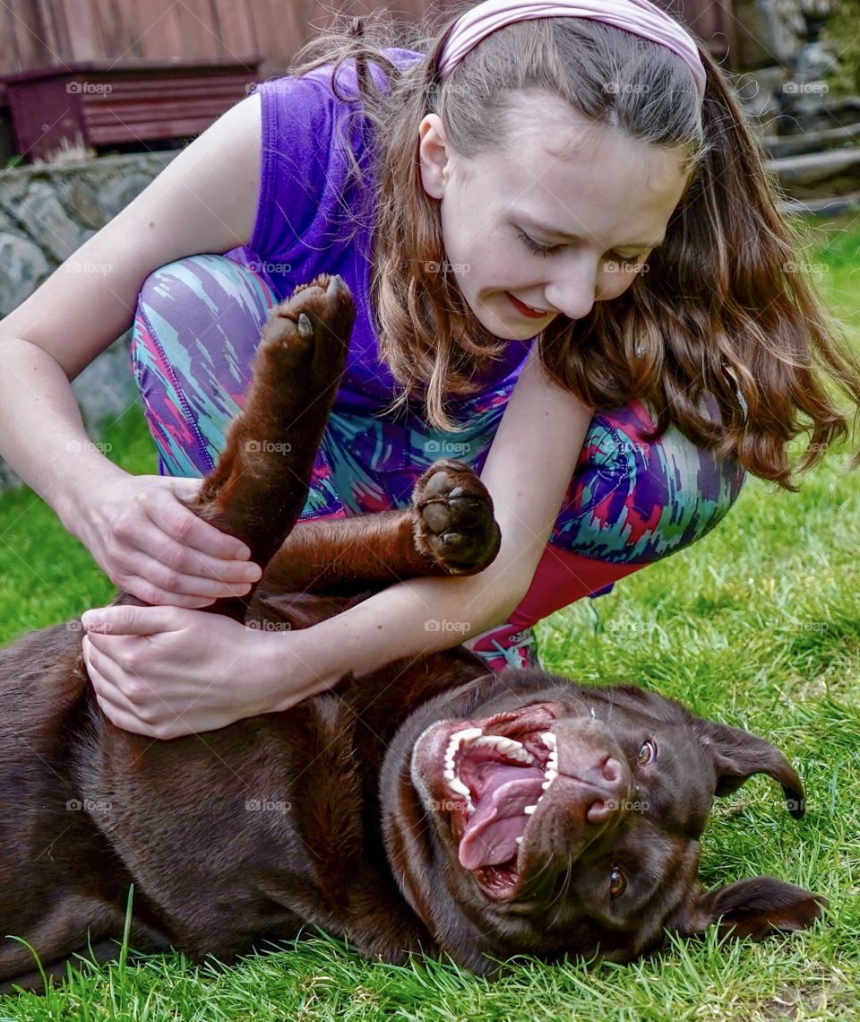 Girl and her dog smile and laugh while playing