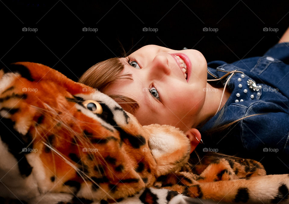 On the head toy leopard lying cheerful little girl and looking up