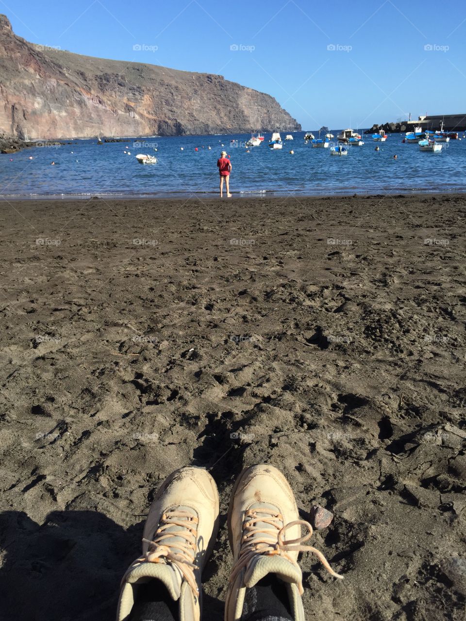 Hiking shoes on the feet while sitting on the Beach and enjoying the sea view 