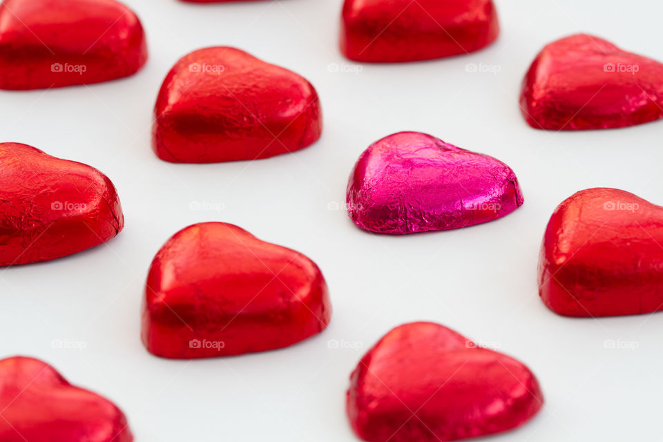 Valentine's Day heart shaped chocolates lined up in rows on a white background.