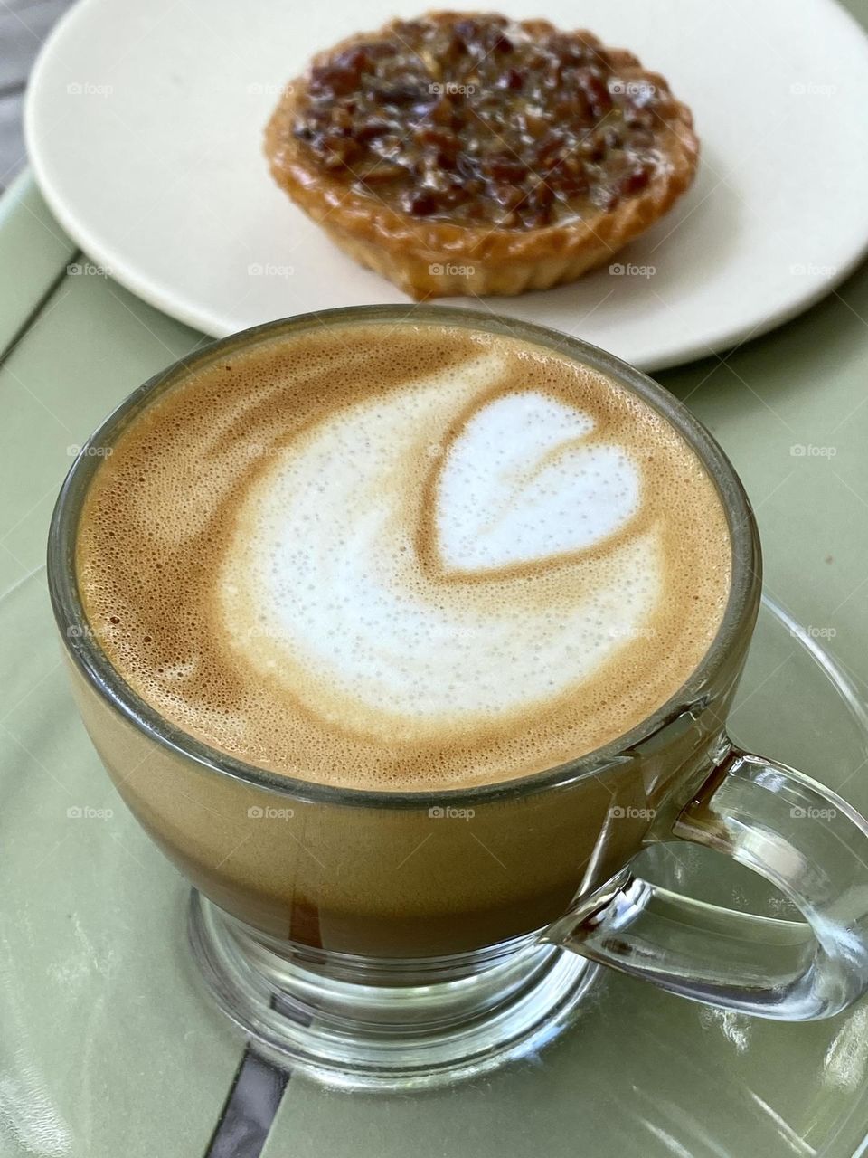 A latte with a heart drawn in the foam and a pecan tart